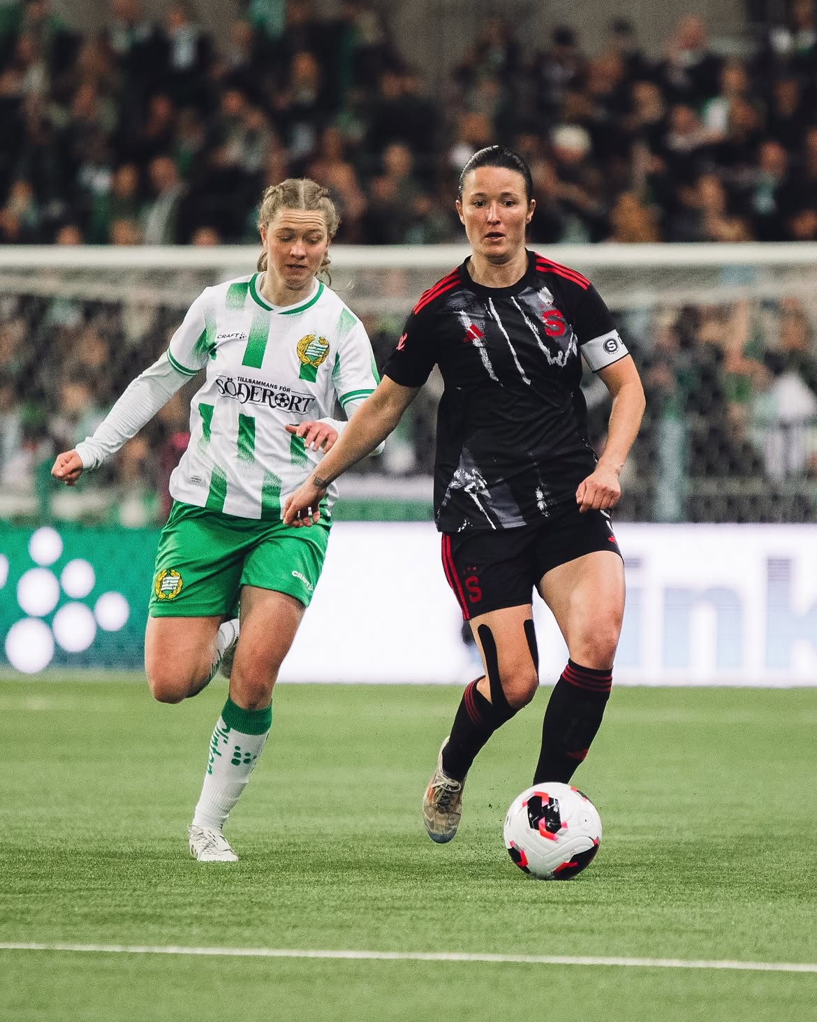 A Sparta Praha player in the black away kit carrying the ball past a Hammarby opponent